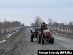 Ауыл көшесінде кетіп бара жатқан трактор.