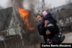 Киевке жақын Ирпень қаласына шабуыл жасалғанда қашып бара жатқан ер адам мен бала. 6 наурыз 2022 жыл.