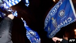 Leicester City fans wave flags as they celebrates their team becoming the English Premier League football champions in central Leicester, eastern England