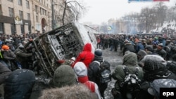 Шерушілер өртенген полиция көлігін төңкеріп жатыр. Киев, 21 қаңтар 2014 жыл.