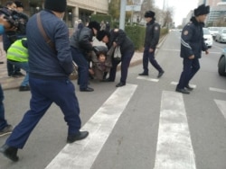 Полицейлер "рұқсат етілмеген митинг өтеді" деген жерде әйелді ұстап әкетіп барады. Нұр-Сұлтан, 26 қазан 2019 жыл.