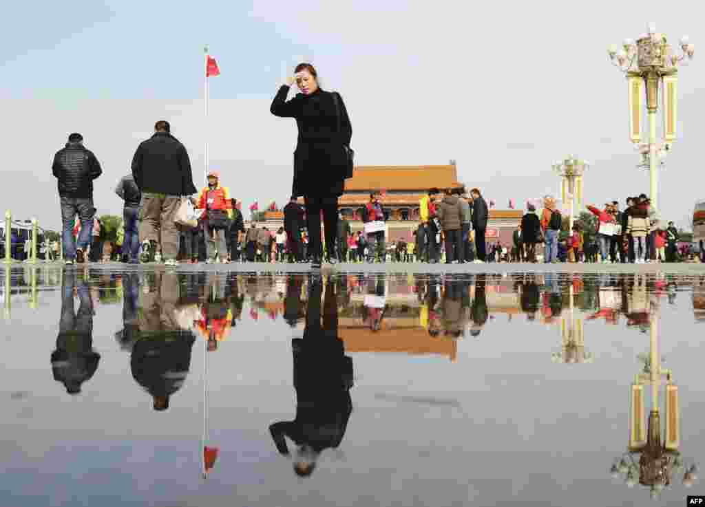 Pekində Tiananmen Meydanı yaxınlığında gəzişən paytaxt sakinləri.